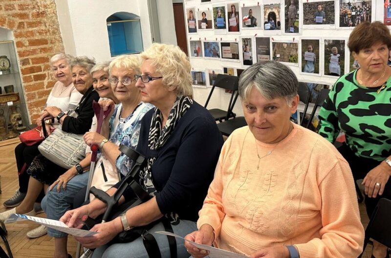 Seniorzy z DDS+ siedzą na spotkaniu poświęconym Polskim Dzieciom Wojny