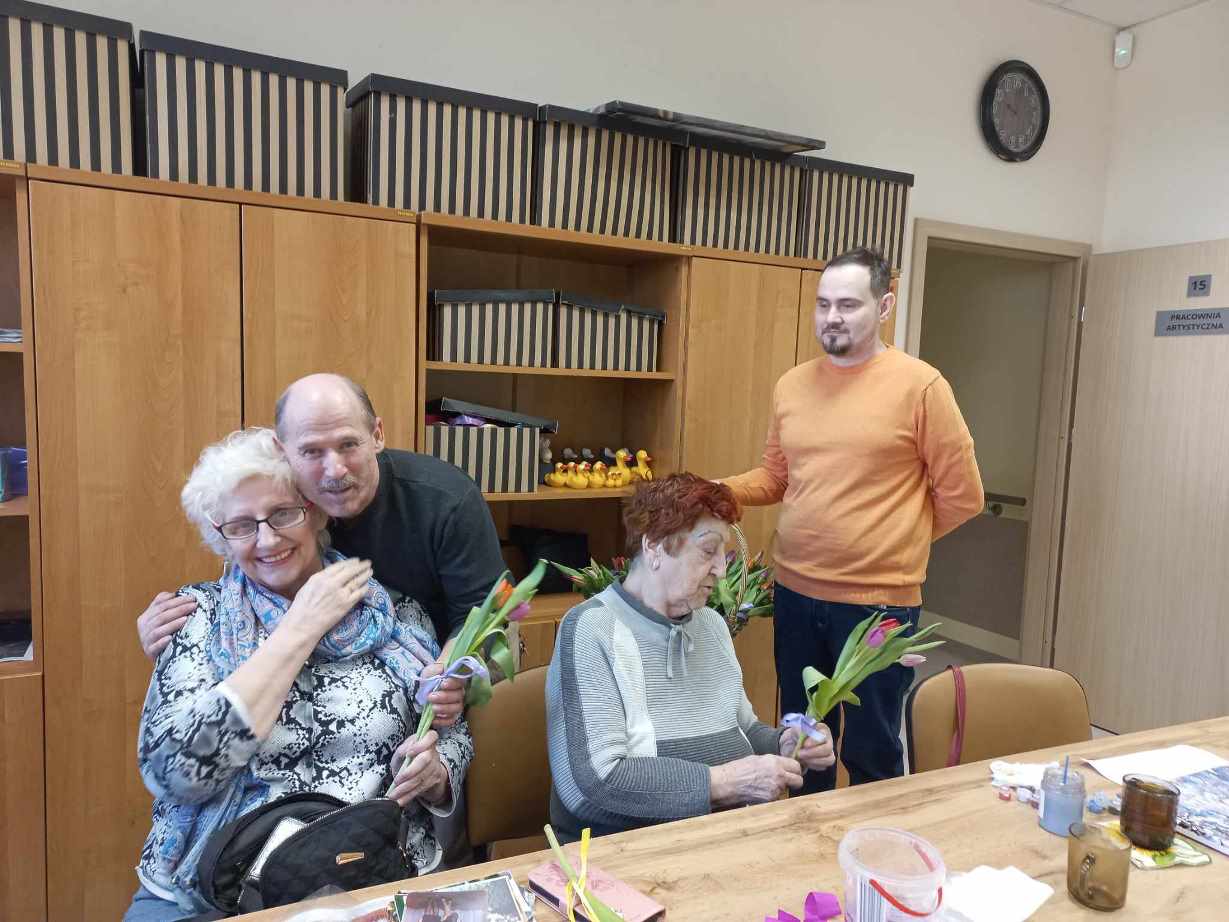 Mężczyźni wręczają kwiatki Paniom z ośrodka