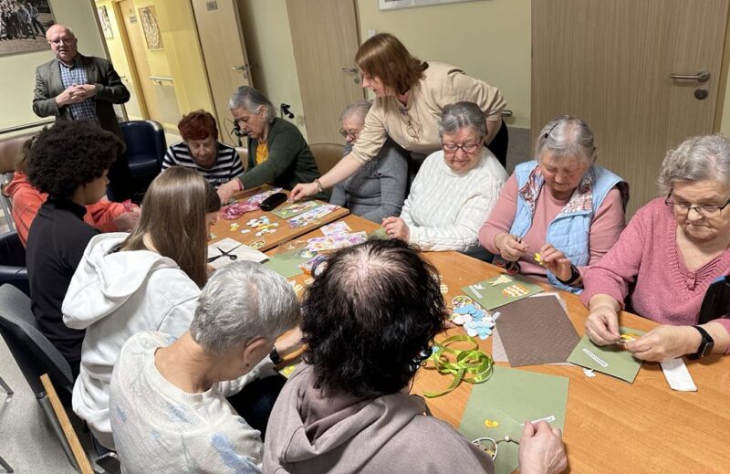 Seniorzy z DDS+ wraz z młodzieżą ze Szkoły Podstawowej w Sieniawie Żarskiej wykonują kartki wielkanocne przy stole
