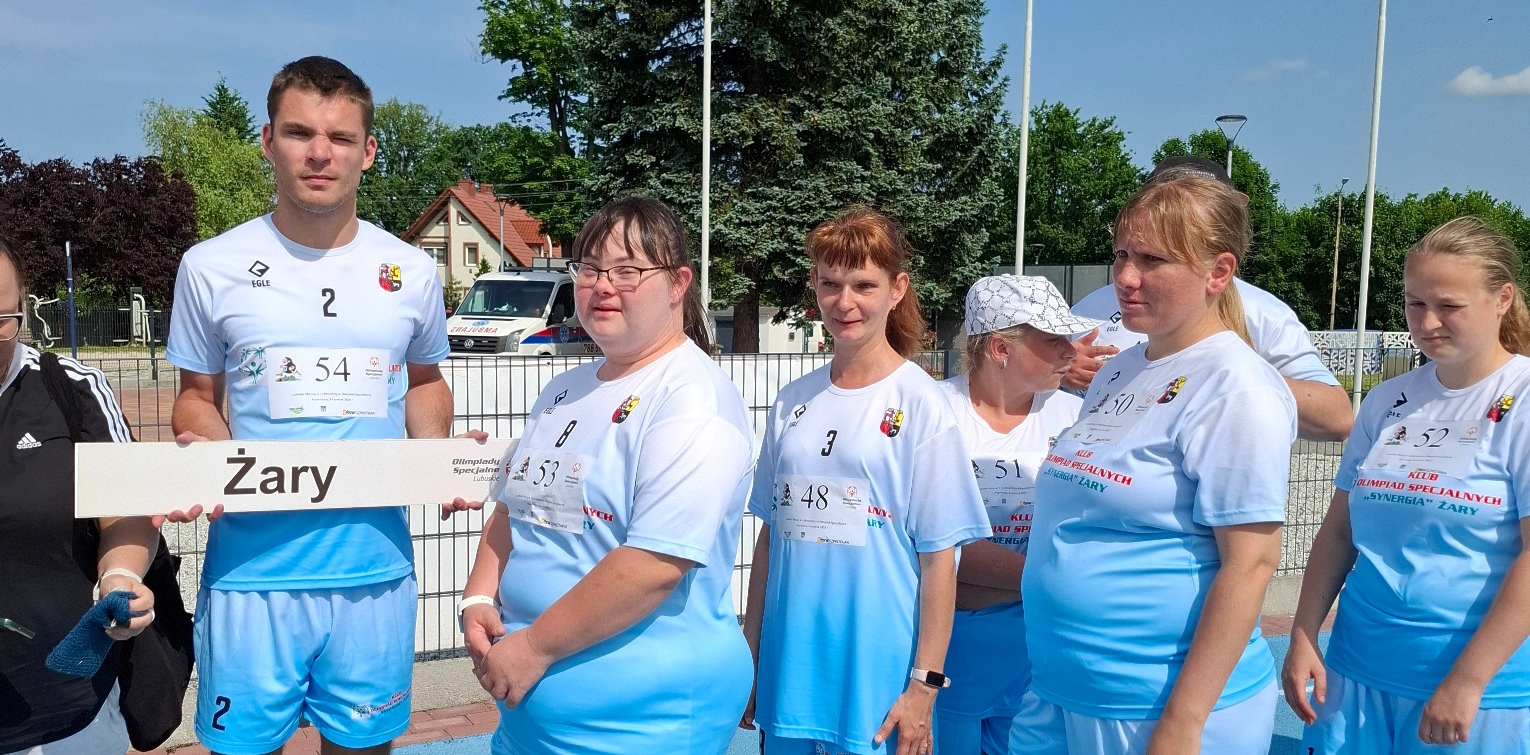 7 sportowców z niepełnosprawnościami w błękitnych strojach podczas prezentacji drużyny, przed rozpoczęciem rywalizacji lekkoatletycznej