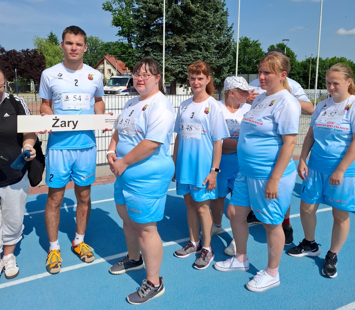 7 sportowców z niepełnosprawnościami w błękitnych strojach podczas prezentacji drużyny, przed rozpoczęciem rywalizacji lekkoatletycznej